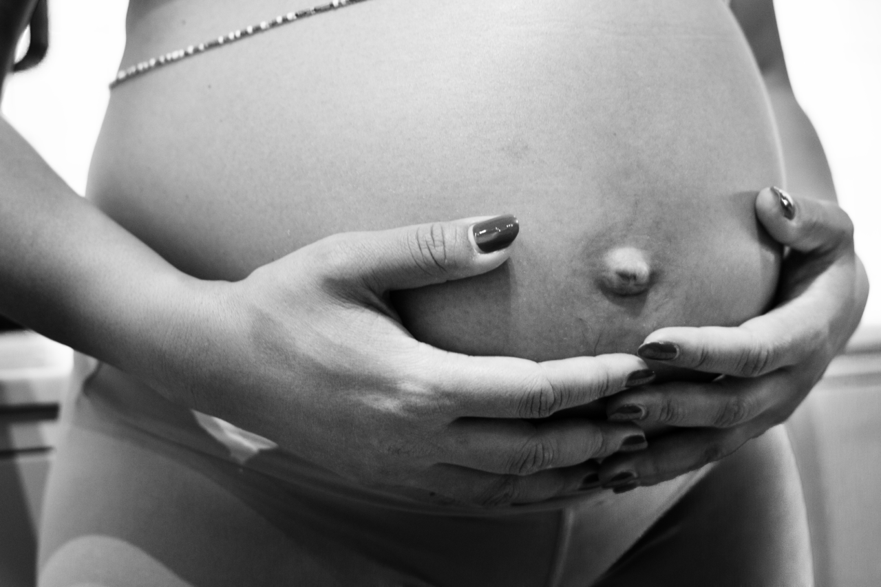 Gravid kvinna med händerna på magen